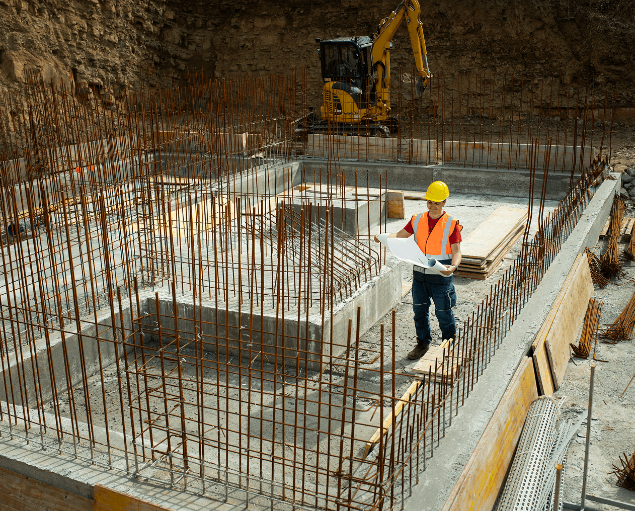 Builder inspecting foundation with plans
